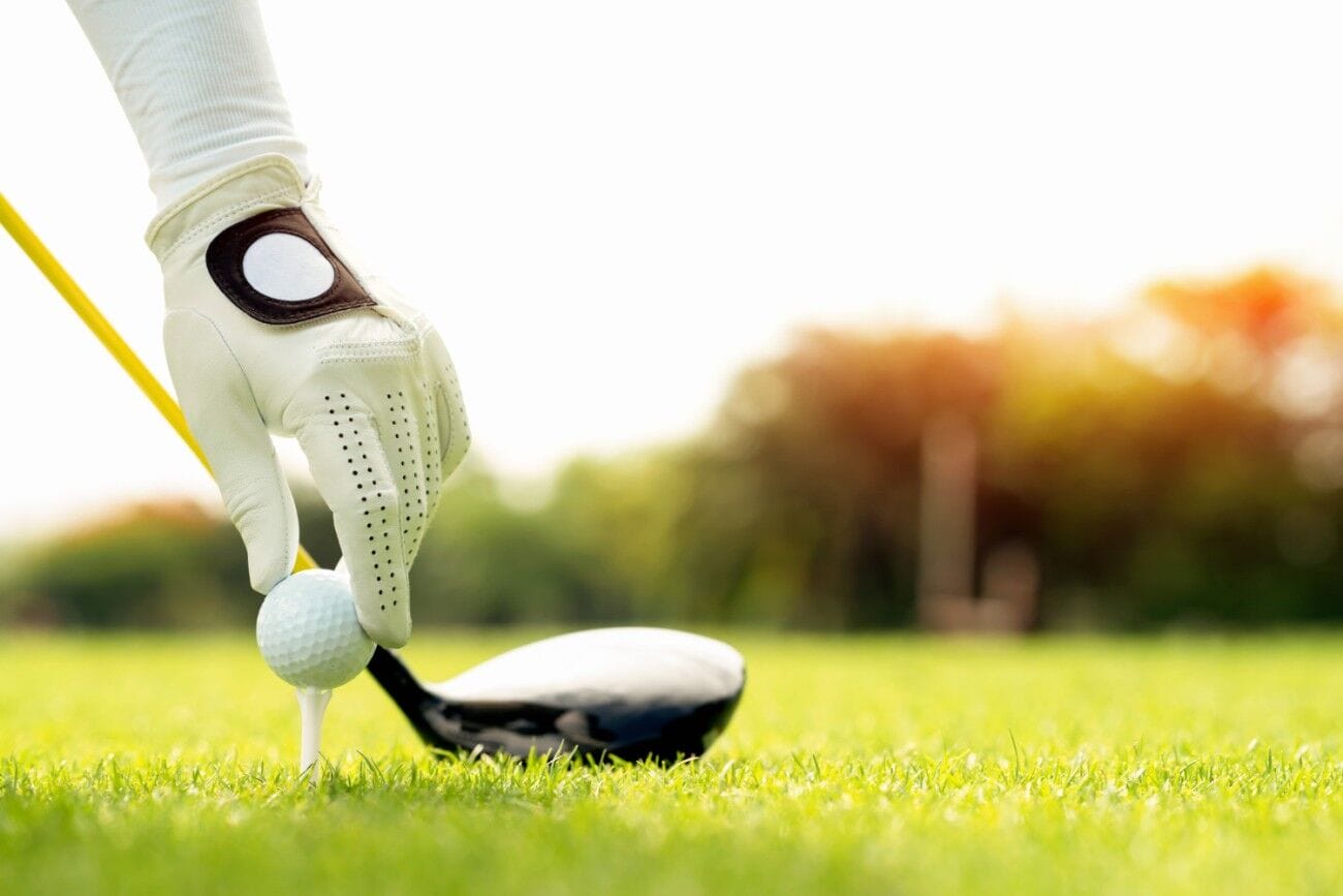 Why Suvarnabhumi Golf and Country Club Should Be Your Next Golfing Destination in Thailand 2 A hand is positioned holding a golf ball with a tee on the course, ready for tee off. There is copy space available on the right side.