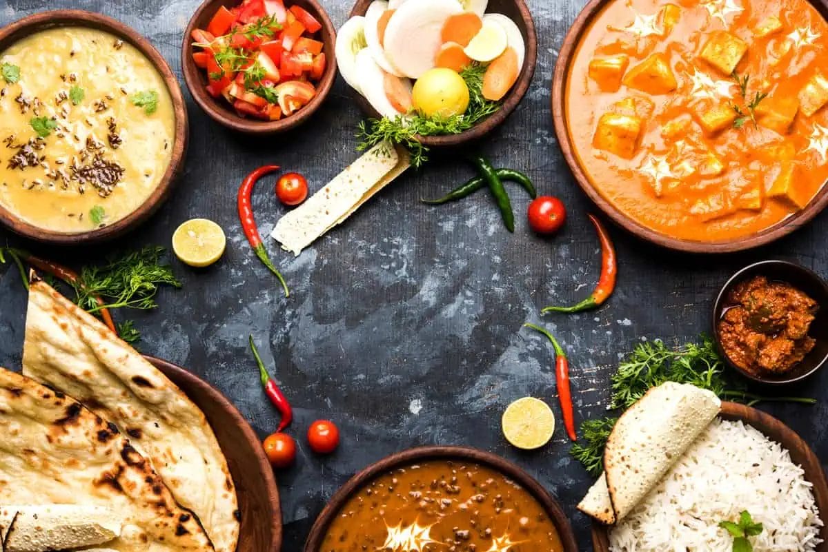 Top Indian Restaurants in Pattaya: Discover the Best Indian Food and Vegetarian Delights 2 A vibrant array of Indian cuisine, featuring curry, dal, rice, naan, and garnishes on a rustic backdrop