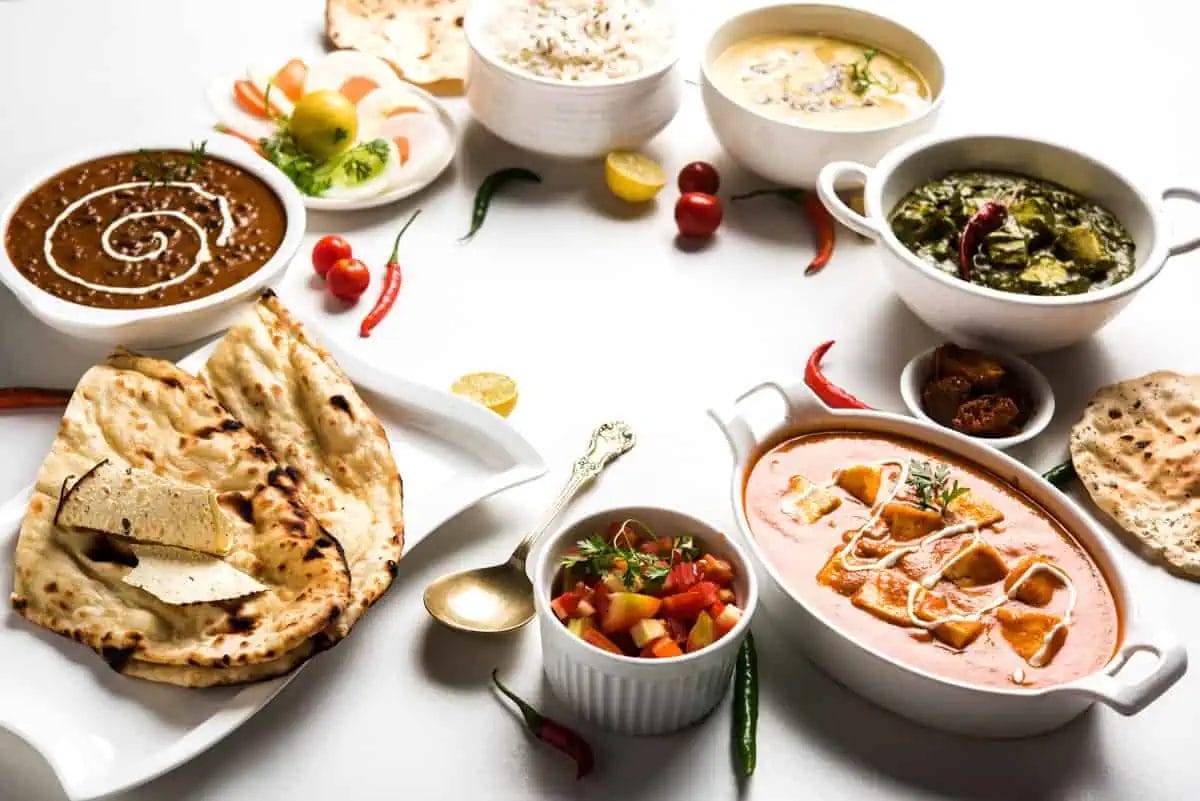An elegant North Indian meal with creamy curries, breads, and a side salad, ready to be savored