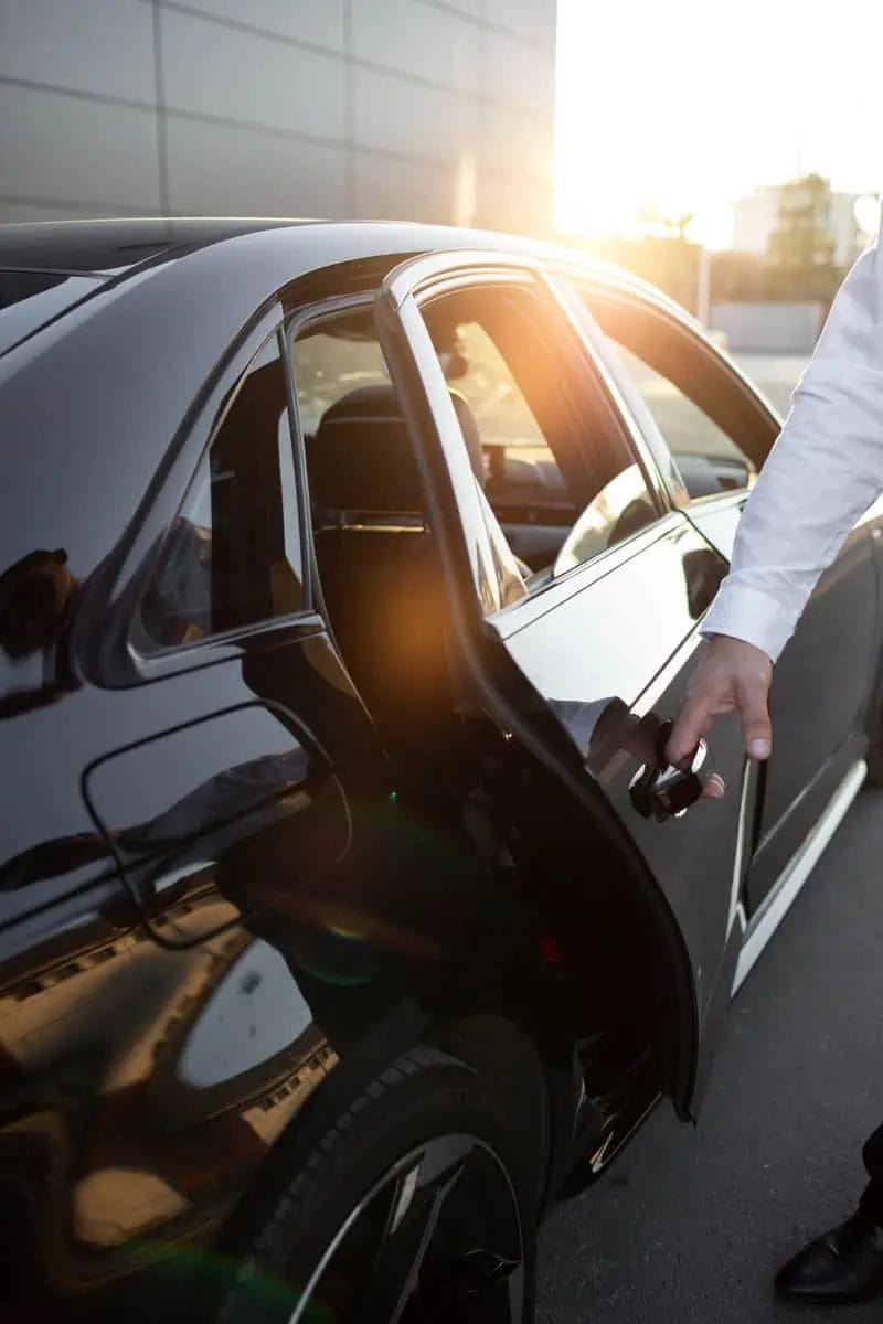 Chauffeur opening the door of a luxury black car