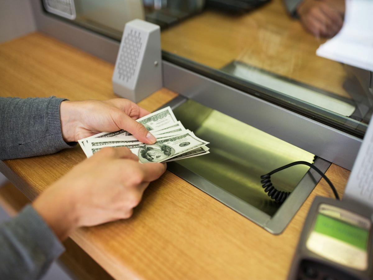 Concept of people, savings, cash withdrawal, and finance - a customer's hands exchanging money at a bank office or currency exchange