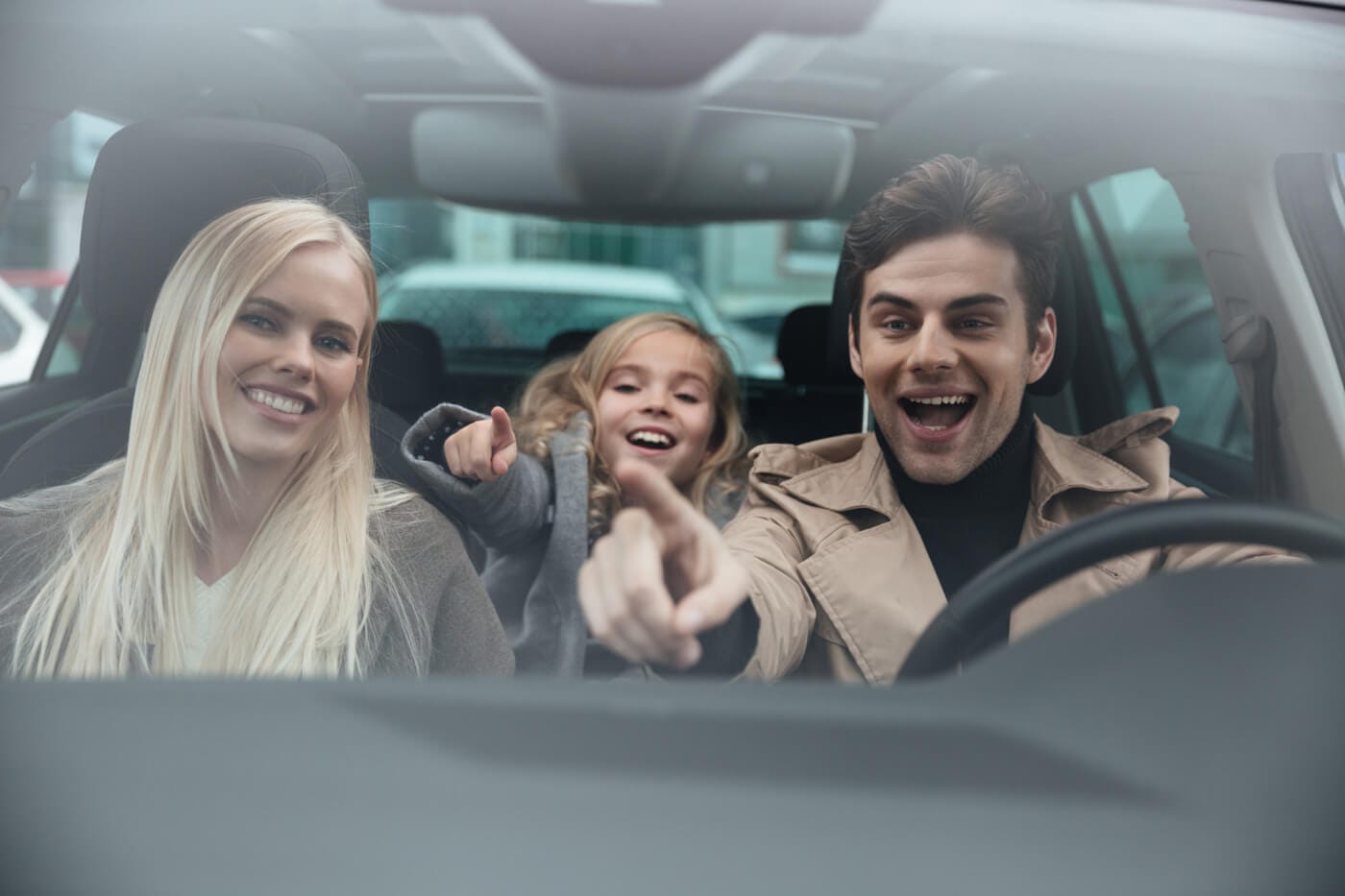 Joyful man in a taxi car with his wife and daughter