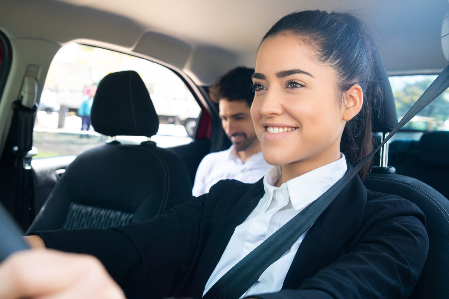 Portrait of a young female taxi driver with a businessman in the back seat